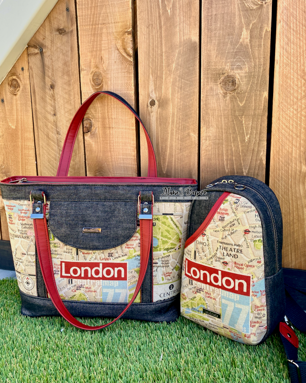 Two coordinating black denim bags, one a tote, the other a sling bag, with 'London' printed on the front and red handles on grass against wooden background.