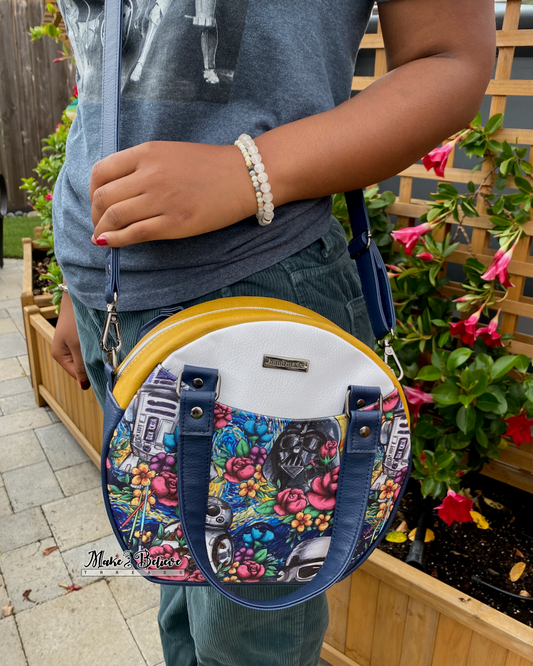 Person wearing a floral space wars round crossbody bag with floral design in an outdoor setting