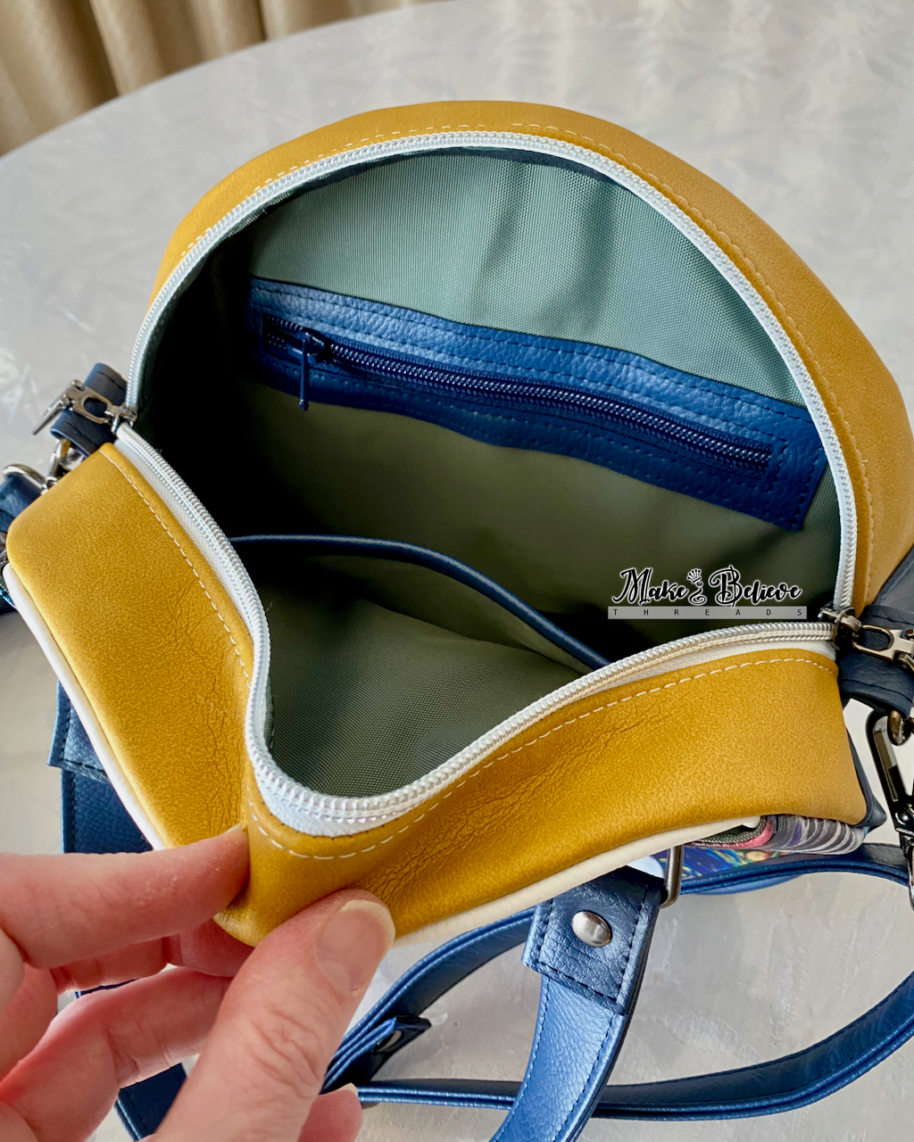 View through the open yellow zipper gusset revealing a great interior with blue-accented slip pocket and zipper pocket