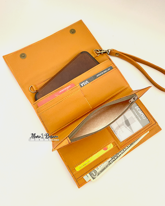 Open view of ochre tri-fold wallet filled with a cell phone, credit cards, and cash, and the zipper pocket open revealing a beige floral interior on a neutral background