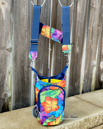 Colorful floral-patterned water bottle carrier with straps hanging on a metal rod against a wooden background.