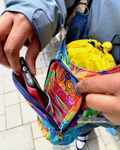 A person is sliding a phone into one of the slip pockets in the front pouch of a colorful water bottle carrier.