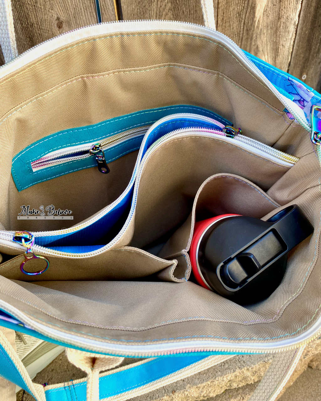 Above view of an open tote bag with beige interior, an interior zipper pocket, a center divider zipper pocket, and 2 cargo slip pockets.