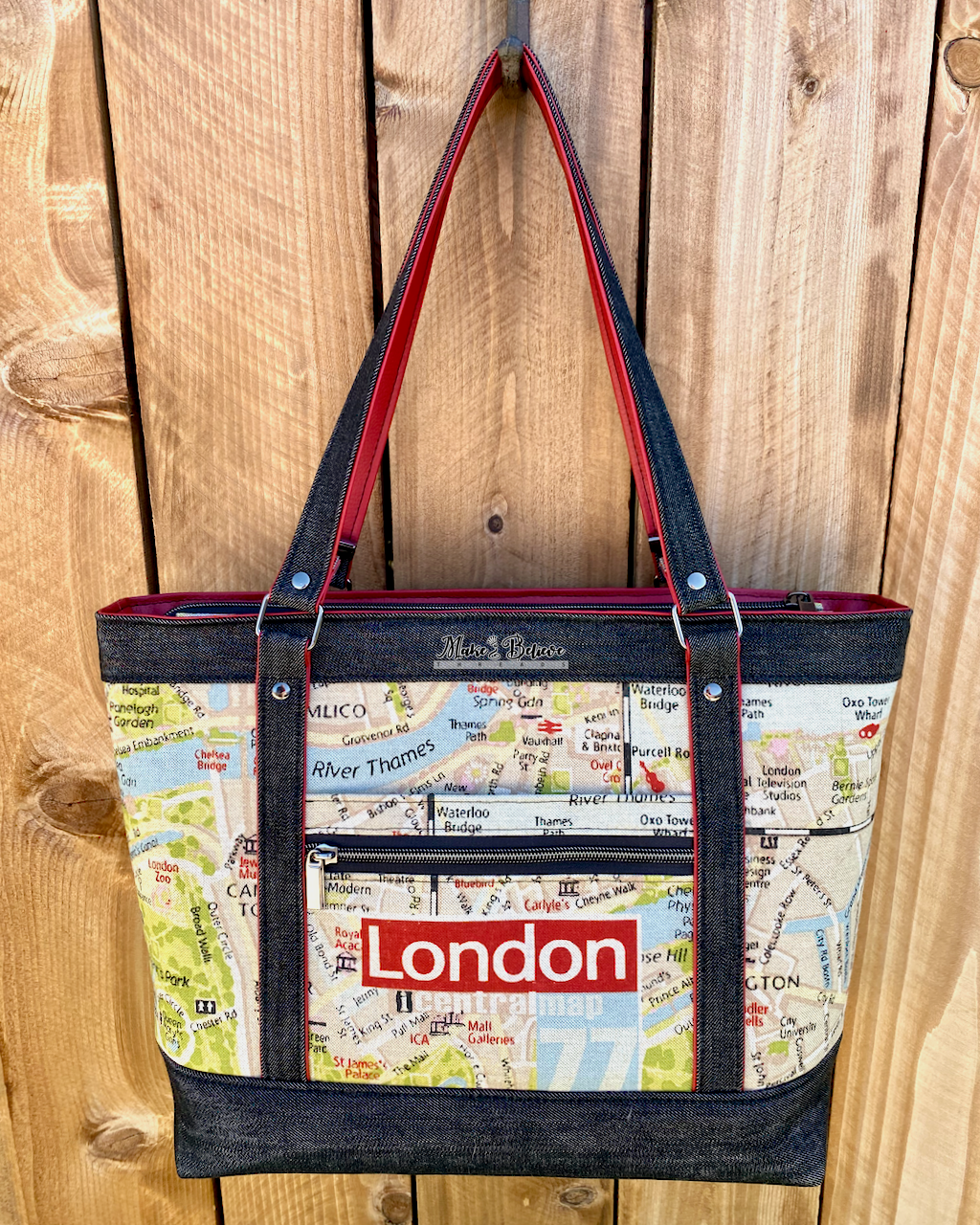 Black denim tote bag with London map design and red accents on a wooden background