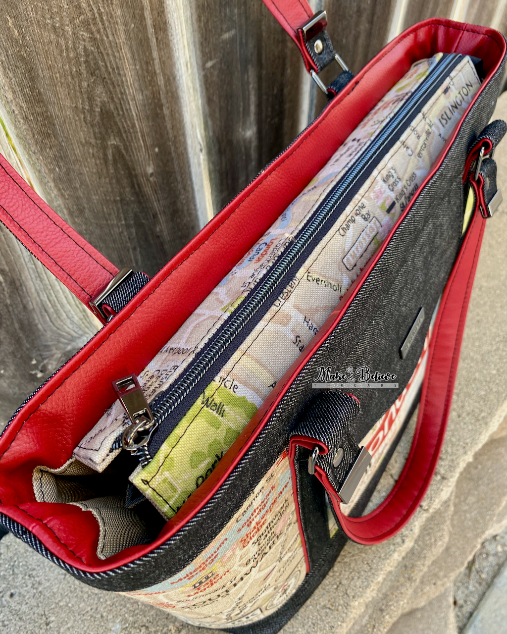 Above view of black denim tote's zipper panel closure on a wooden surface