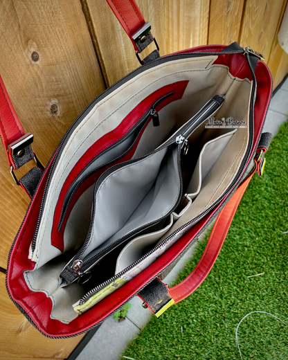 Interior view of a black denim tote bag showing a beige and gray interior with a zipper pocket, 2 cargo slip pockets, and a zippered center divide pocket on a grass and wood background