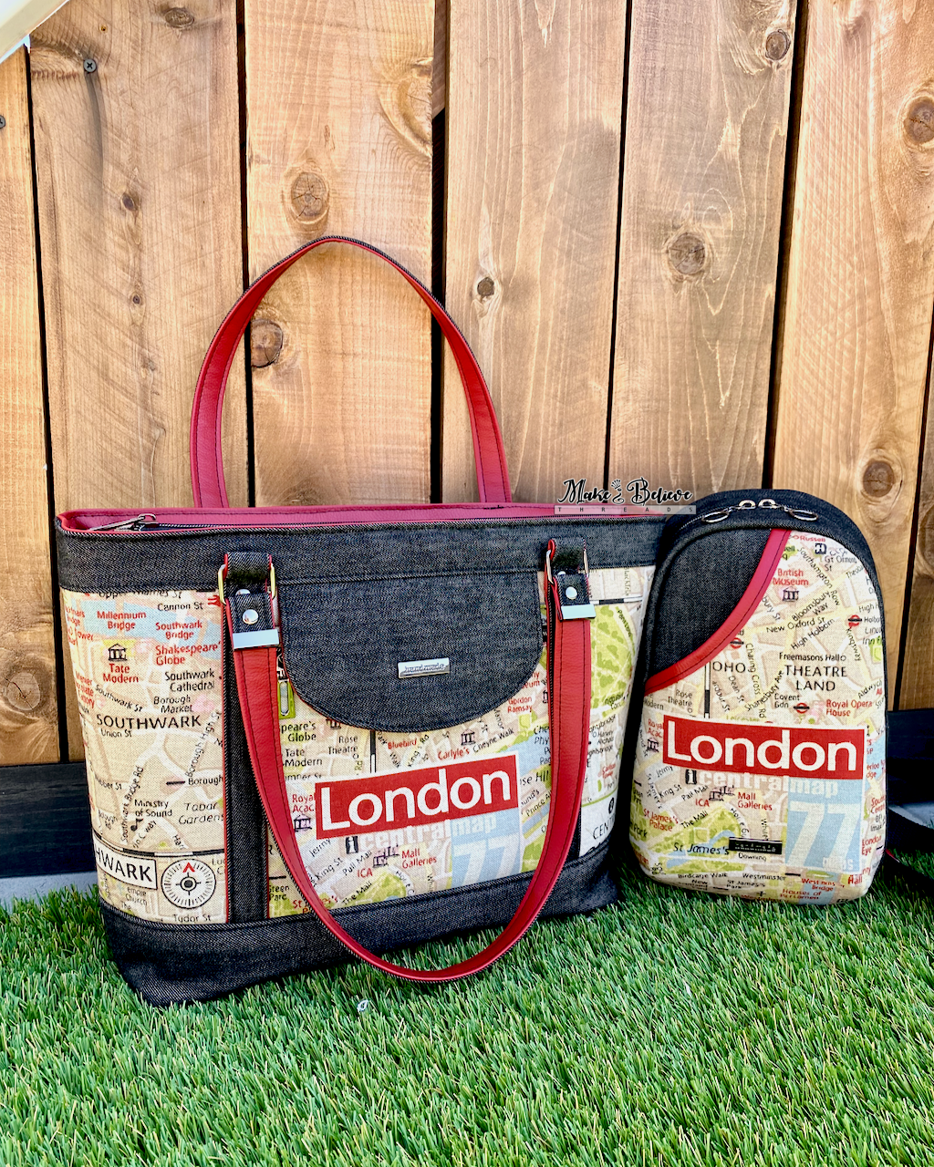 Two coordinating black denim bags, one a tote, the other a sling bag, with 'London' printed on the front and red handles on grass against wooden background.