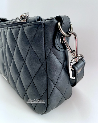 Gusset view of a quilted charcoal black shoulder bag with gunmetal strap hardware on a white background