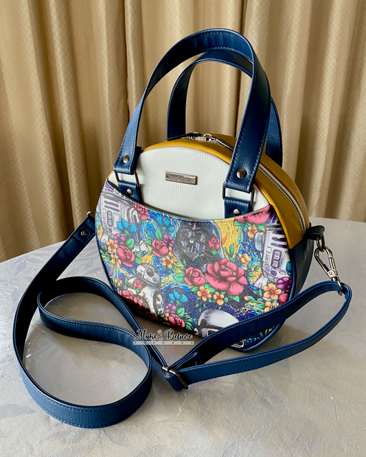 Floral space wars patterned handbag with blue straps on a table