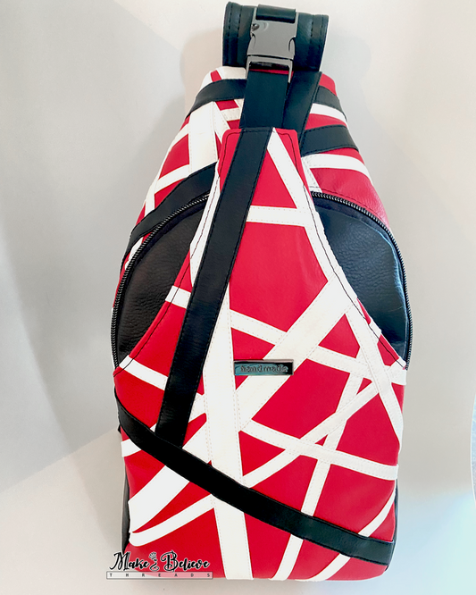 Red, white, and black sling bag on a light gray background. The geometric appliqué design is patterned after Eddie Van Halen's Frankenstrat. 