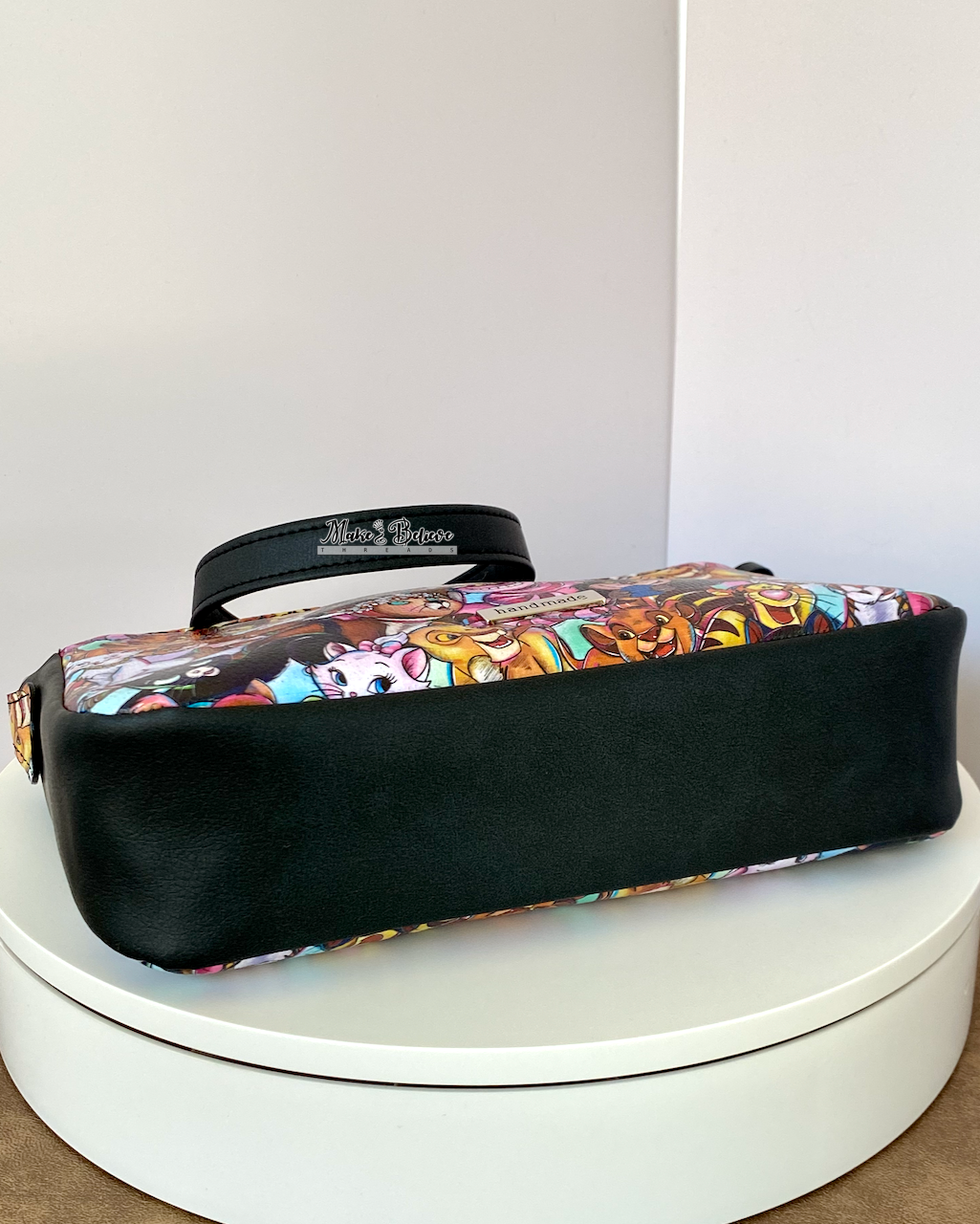 Bottom view of the black faux leather gusset of shoulder bag on a white background