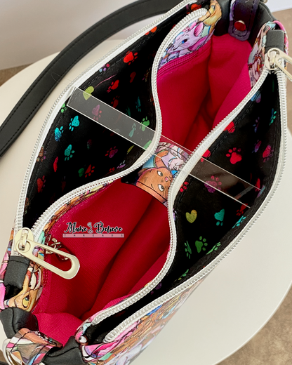 Top view of black shoulder bag with two open zipper pockets revealing colorful paw print pattern on a white background