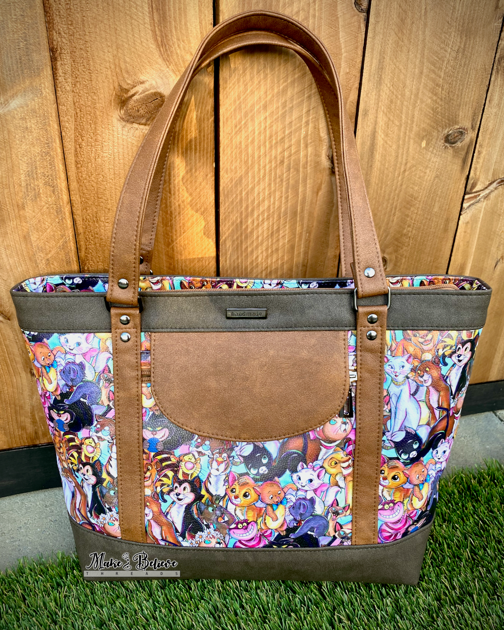 Tote bag with cartoon cats pattern on grass with wooden background