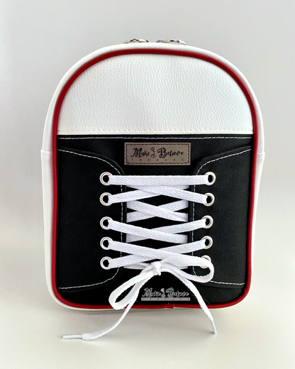 Sling bag designed like a black and white sneaker with white laces on a light gray background