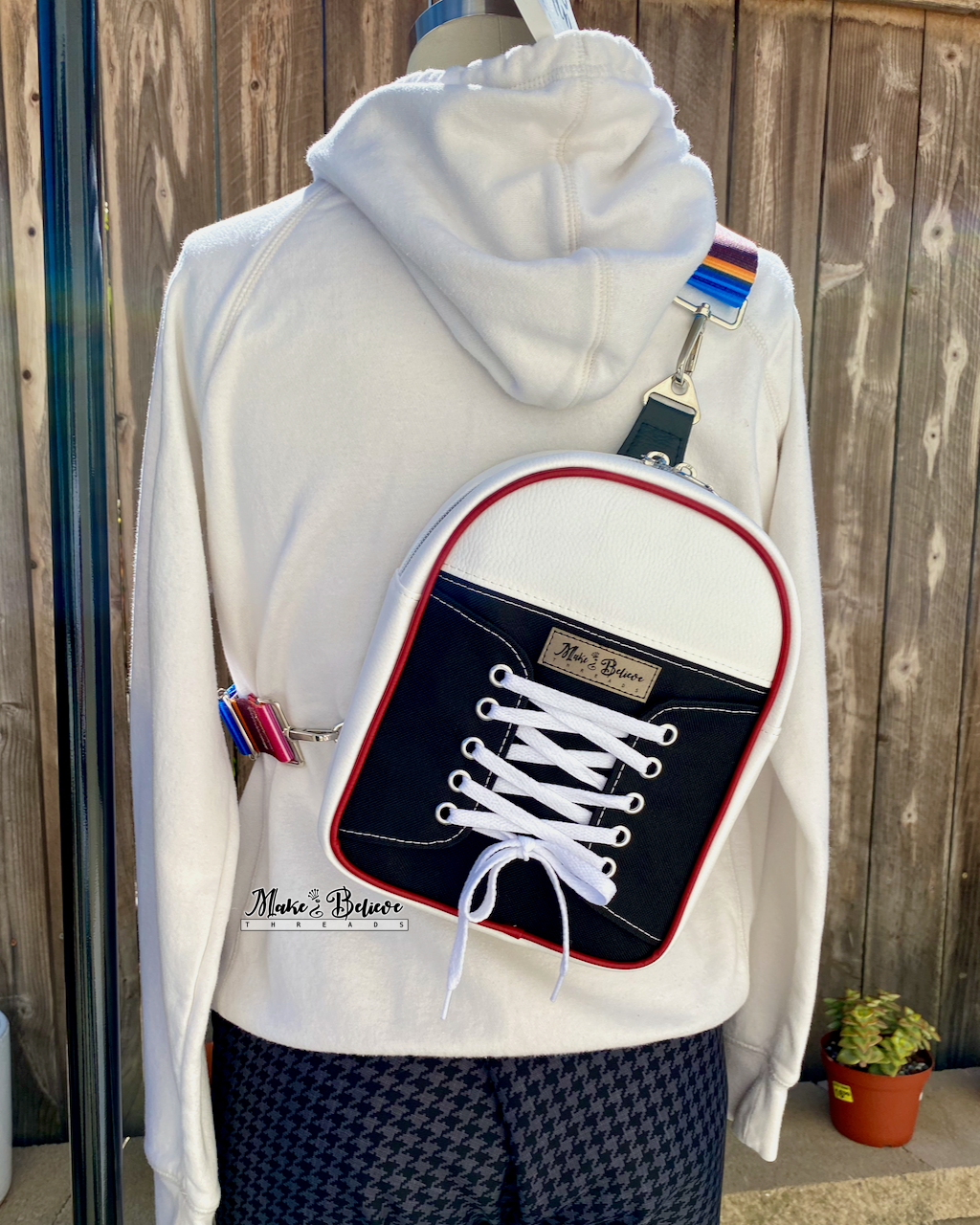 Mannequin wearing a white hoodie with a backpack design resembling a black and white sneaker with white laces