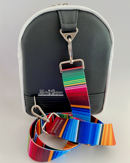 Black of sneaker shaped bag bag with a colorful striped crossbody strap and nickel hardware on a gray background