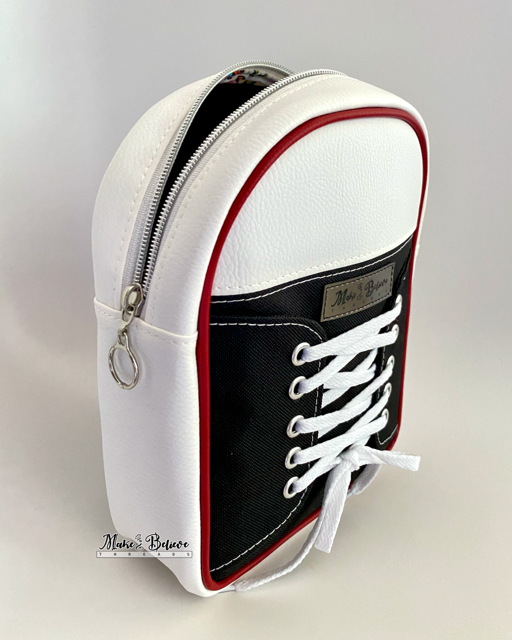 Black and white shoe-shaped sling bag with white laces on a gray background