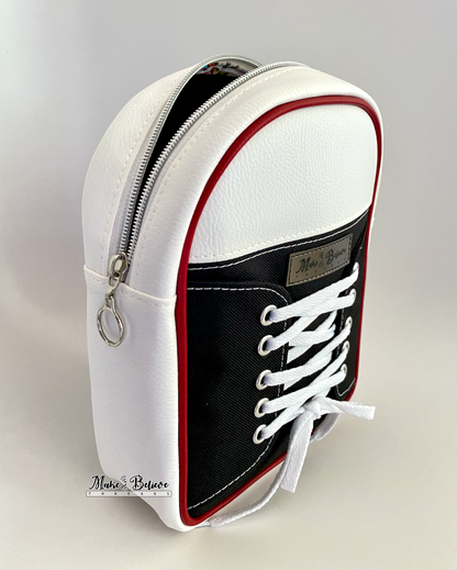 Black and white shoe-shaped sling bag with white laces on a gray background