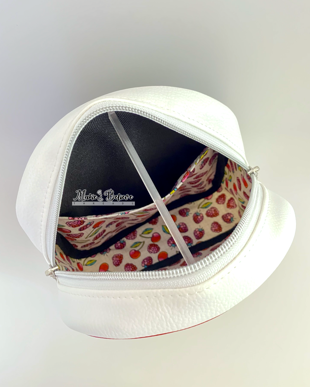 Interior view of sneaker sling bag, containing a fruit-patterned fabric and slip pocket inside, on a light gray background.