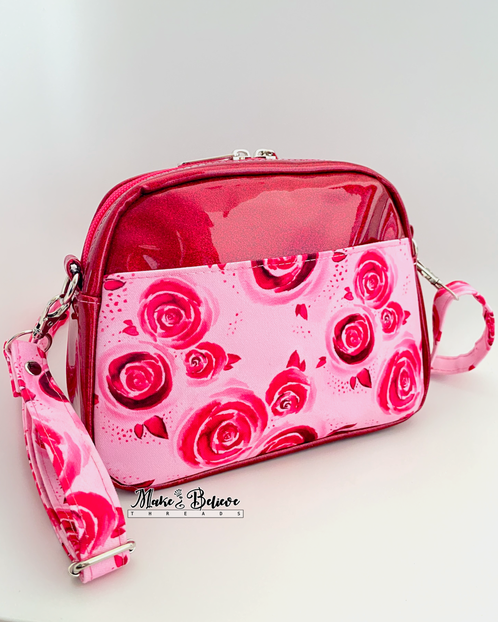 Back slip pocket on pinkish-red glitter crossbody with rose pattern on a white background