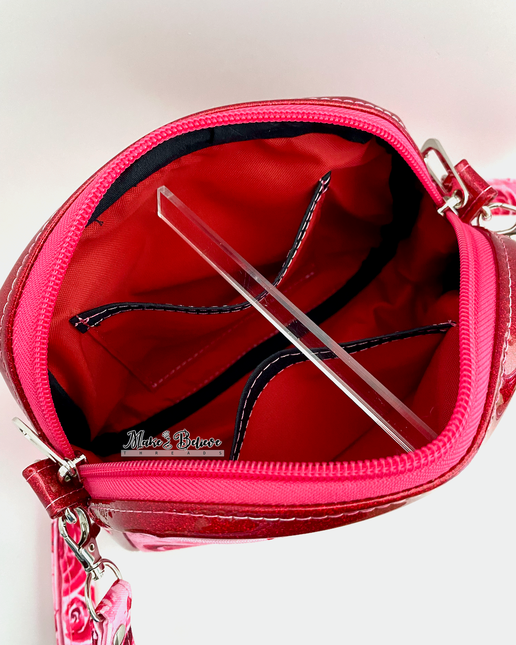 Two slip pockets on a red and black interior of a crossbody bag, photographed on a white background