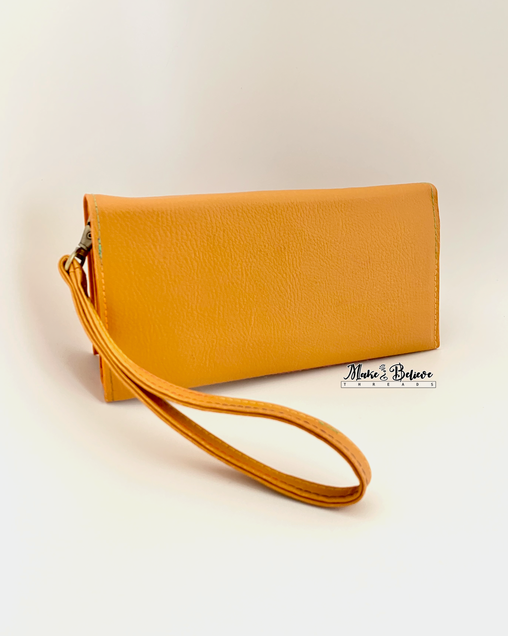 Back of ochre wristlet wallet on a neutral background