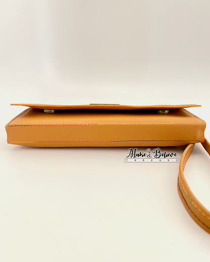 Bottom view of ochre tri-fold wallet revealing magnetic snap closures on a neutral background