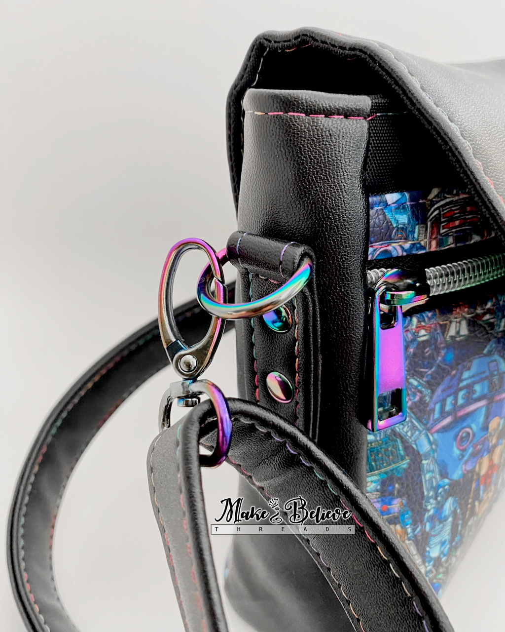Close-up of a black faux leather bag with space wars droids printed vinyl and rainbow metal hardware.