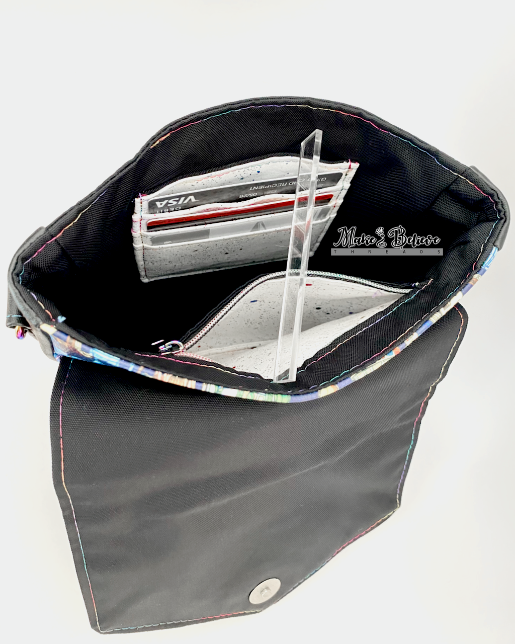 Interior of black faux leather bag with black lining, white zipper pocket, and white card slots all on a white background