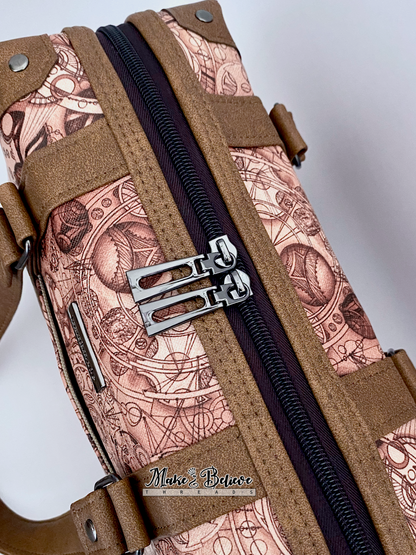 Close-up of steam-trunk and language-pattern detailing of brown faux leather handbag, photographed on a light gray background
