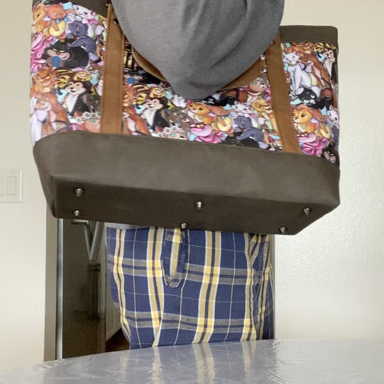 Video of person displaying the exterior and interior features of a cartoon cats travel tote on a dining room table