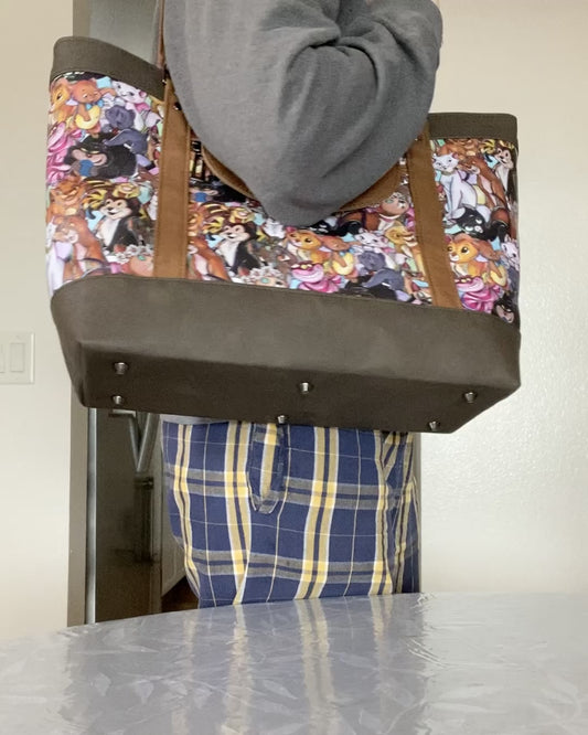 Video of person displaying the exterior and interior features of a cartoon cats travel tote on a dining room table