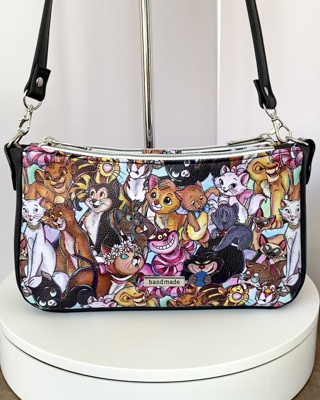 Video of a cartoon cat shoulder bag as it rotates on a turntable, showing all four sides.